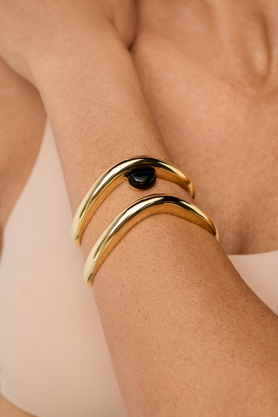 Original gold bracelet with black stone and elegant flowing curve.