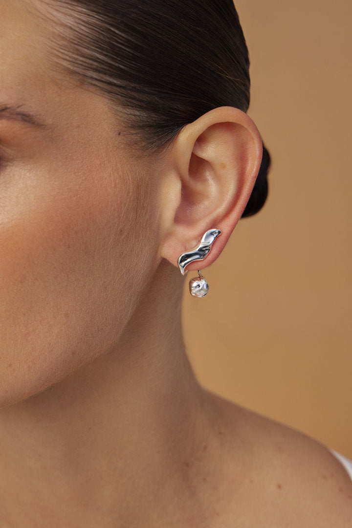 Silver-tone Frida earring featuring organic curves and a spherical detail in a sculptural composition. A contemporary piece that embodies expression, personality, and feminine strength.