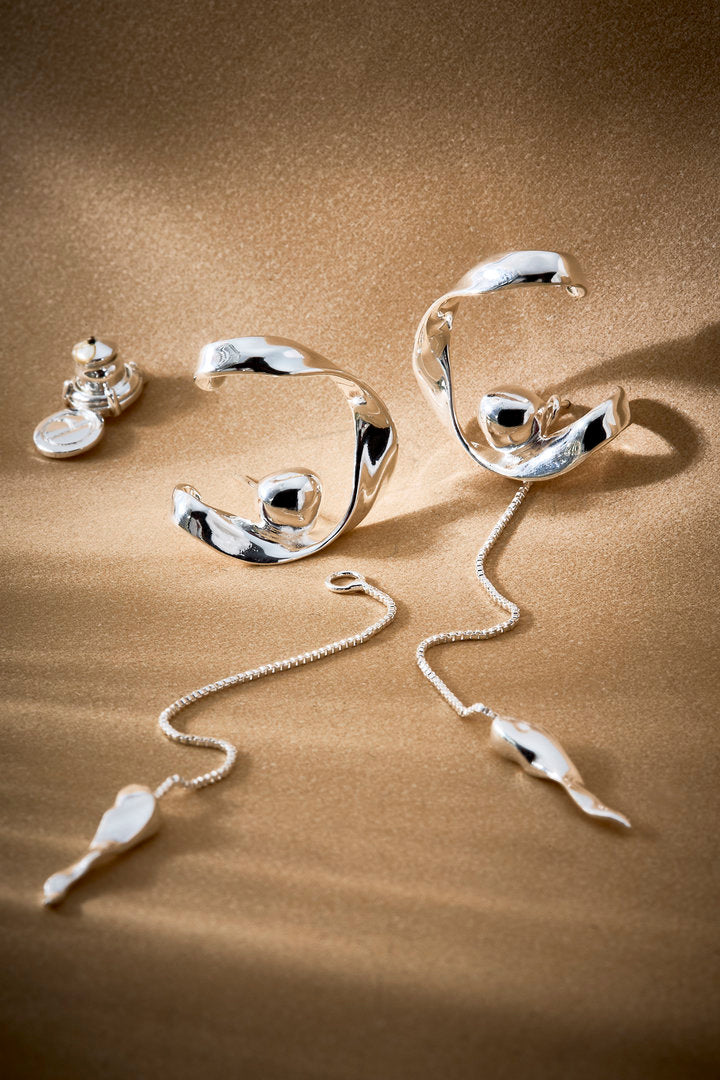 Pair of silver-tone Frida pendulum earrings featuring polished metal and fluidly moving chains.