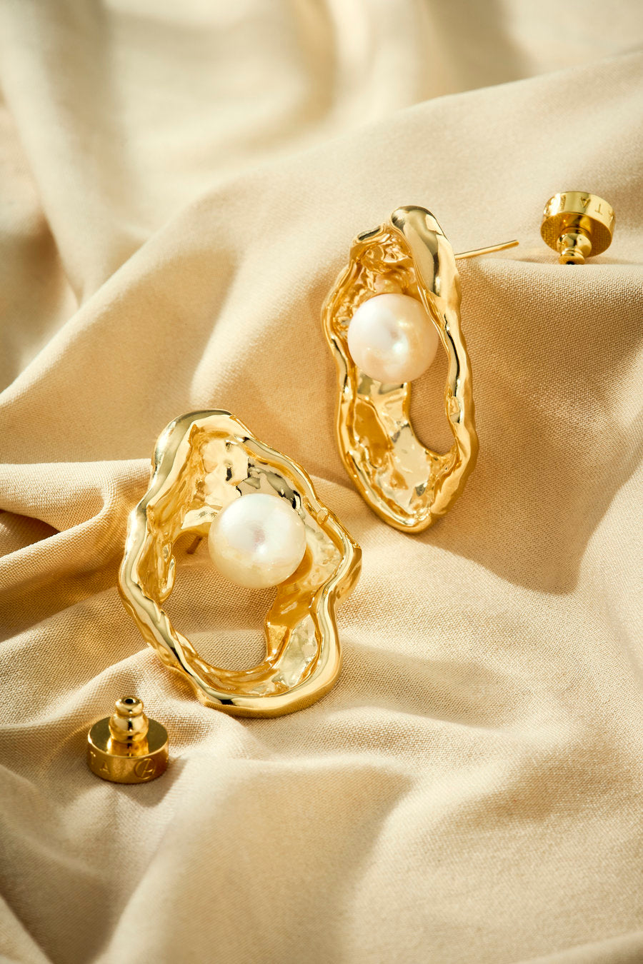 Gold-plated earring with pearl and sculptural organic shape.