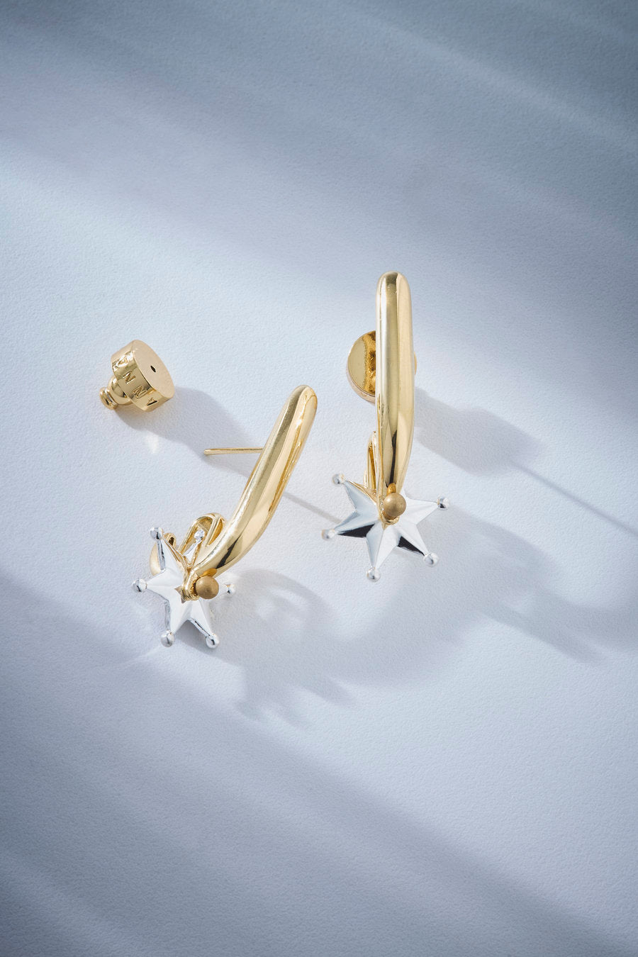 Two-tone gold and silver statement earrings with a sculptural design, polished finish, and silver star, ideal for striking looks.