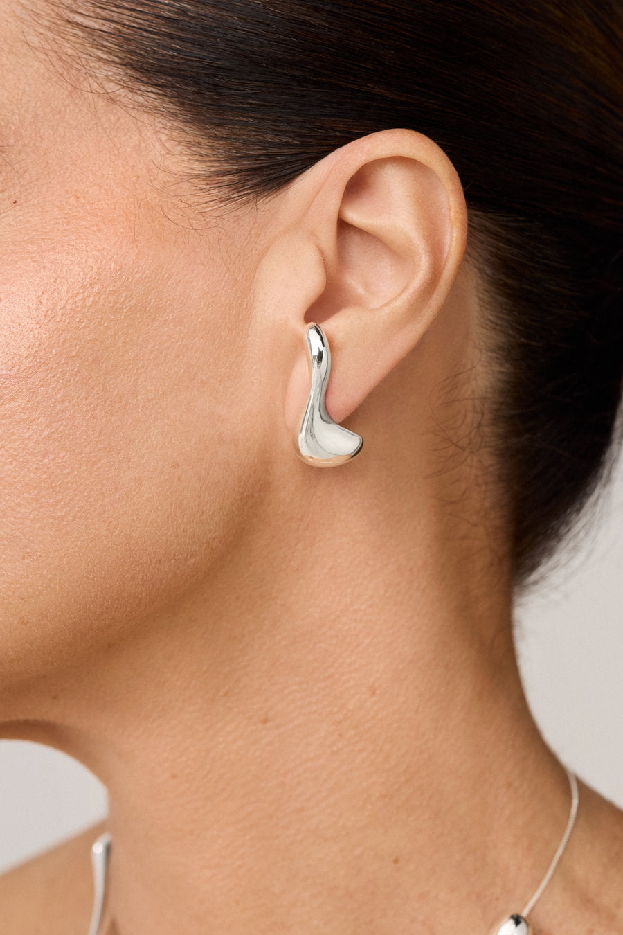 Original silver earring with a sculptural shape that follows the shape of the ear.