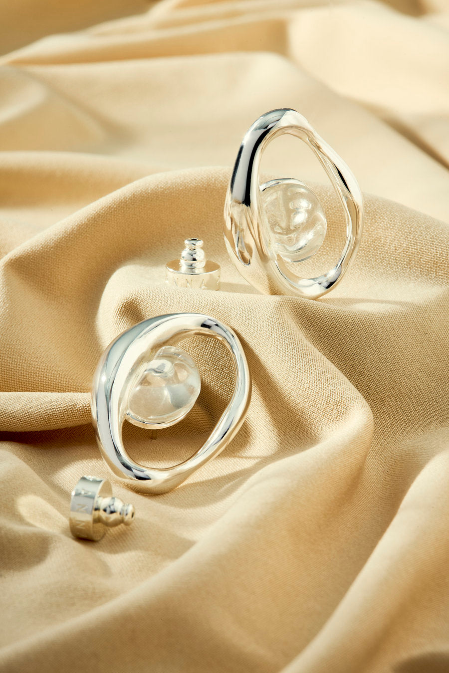 Silver earring with a central crystal and contemporary flowing shapes.