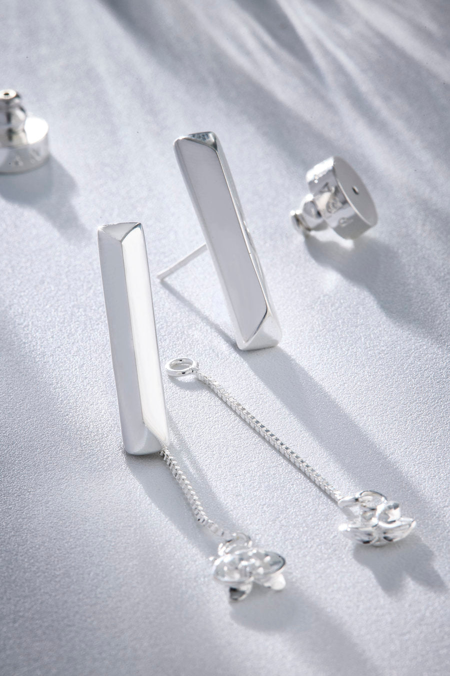 Silver-toned Redemption earrings inspired by faith and maternal love, featuring a vertical bar expressing firmness and a delicate chain symbolizing continuous care.