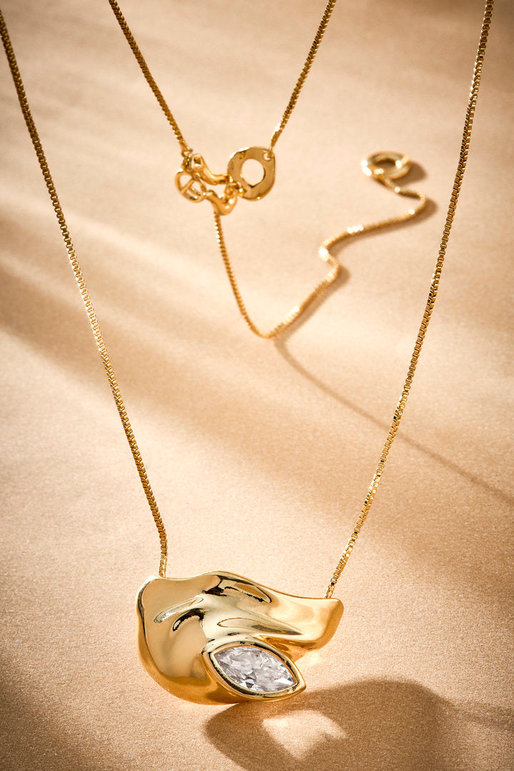 Gold Elsa necklace featuring a faceted crystal and a sculptural pendant for elegant looks.