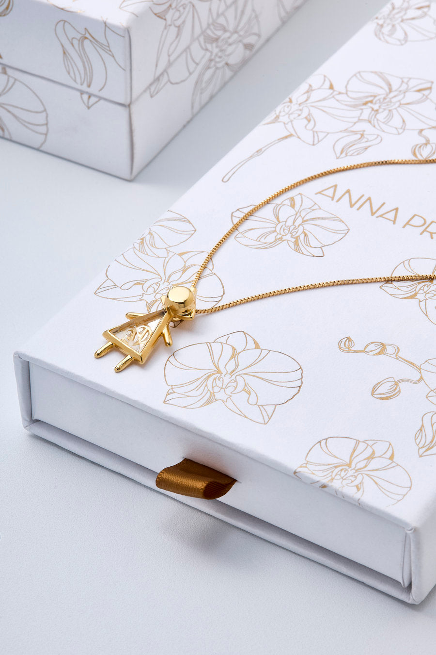 The gold "É Menina" necklace symbolizes the emotion of waiting and the love that blossoms before the encounter, transforming revelation into memory and beginning.