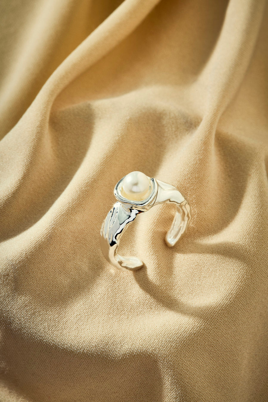 Silver ring with a central pearl and shapes inspired by nature.