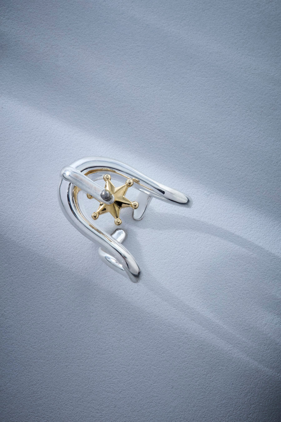 Statement silver ring with a sculptural design, polished finish, and two-tone star detail, ideal for striking looks.
