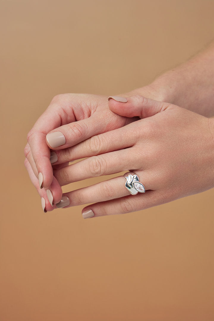 Gold and silver Elsa rings featuring a fluid surface, free-flowing contours, and a navette-shaped Austrian crystal.