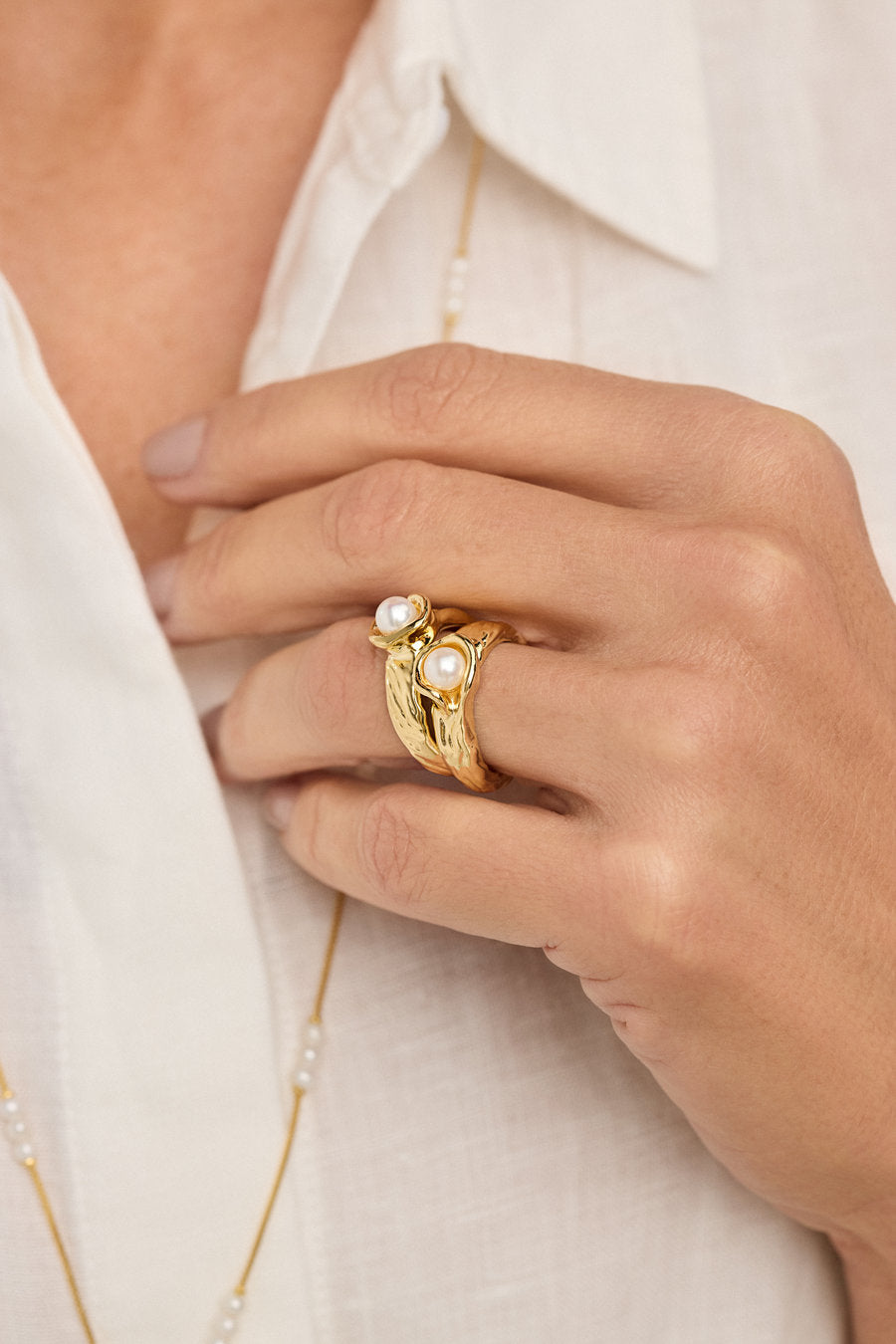 Textured gold ring with a central pearl and nature-inspired shapes.

