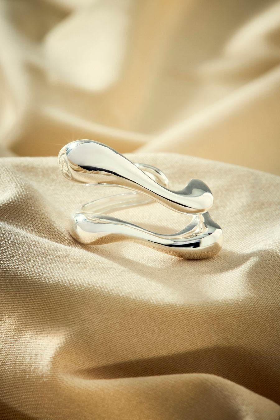 Silver ring with an organic design featuring intertwined shapes.
