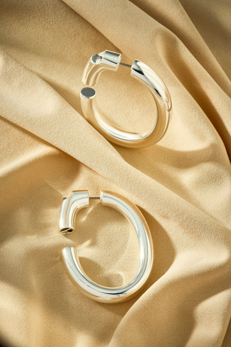 Large silver hoop earring with a curved shape and minimalist design.
