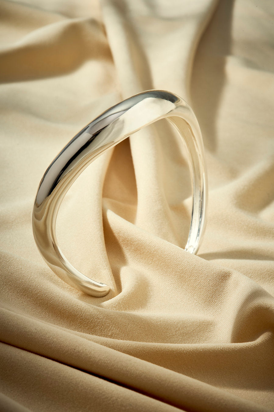 Plain silver gift bracelet with a minimalist design and flowing shape.
