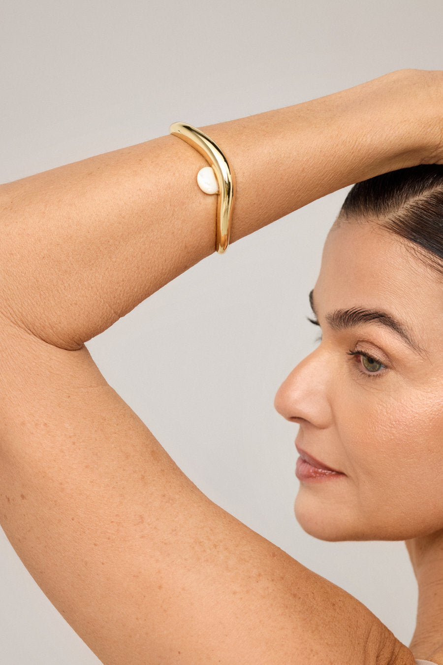 Gold bracelet with a central mother-of-pearl and contemporary flowing lines.