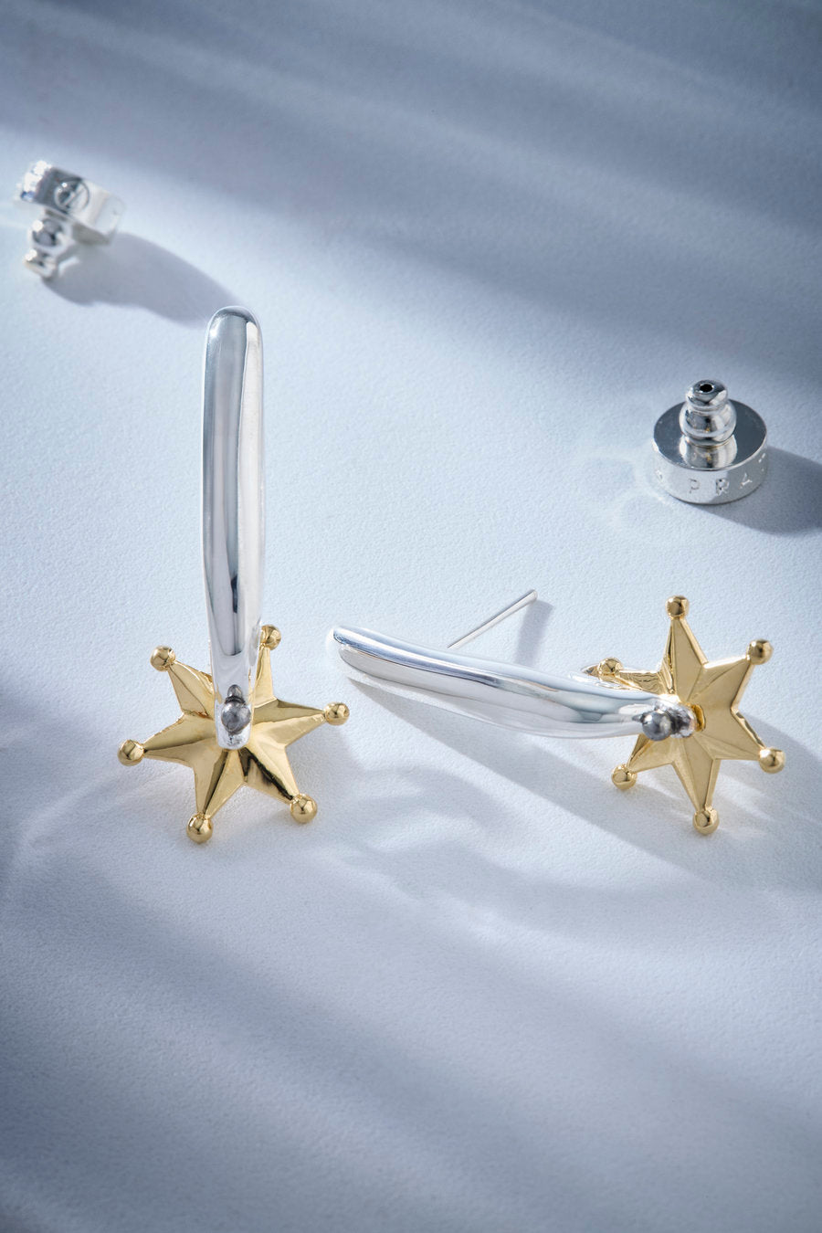 Two-tone sculptural earring with an elongated curved post and a silver-tone star-shaped detail.
