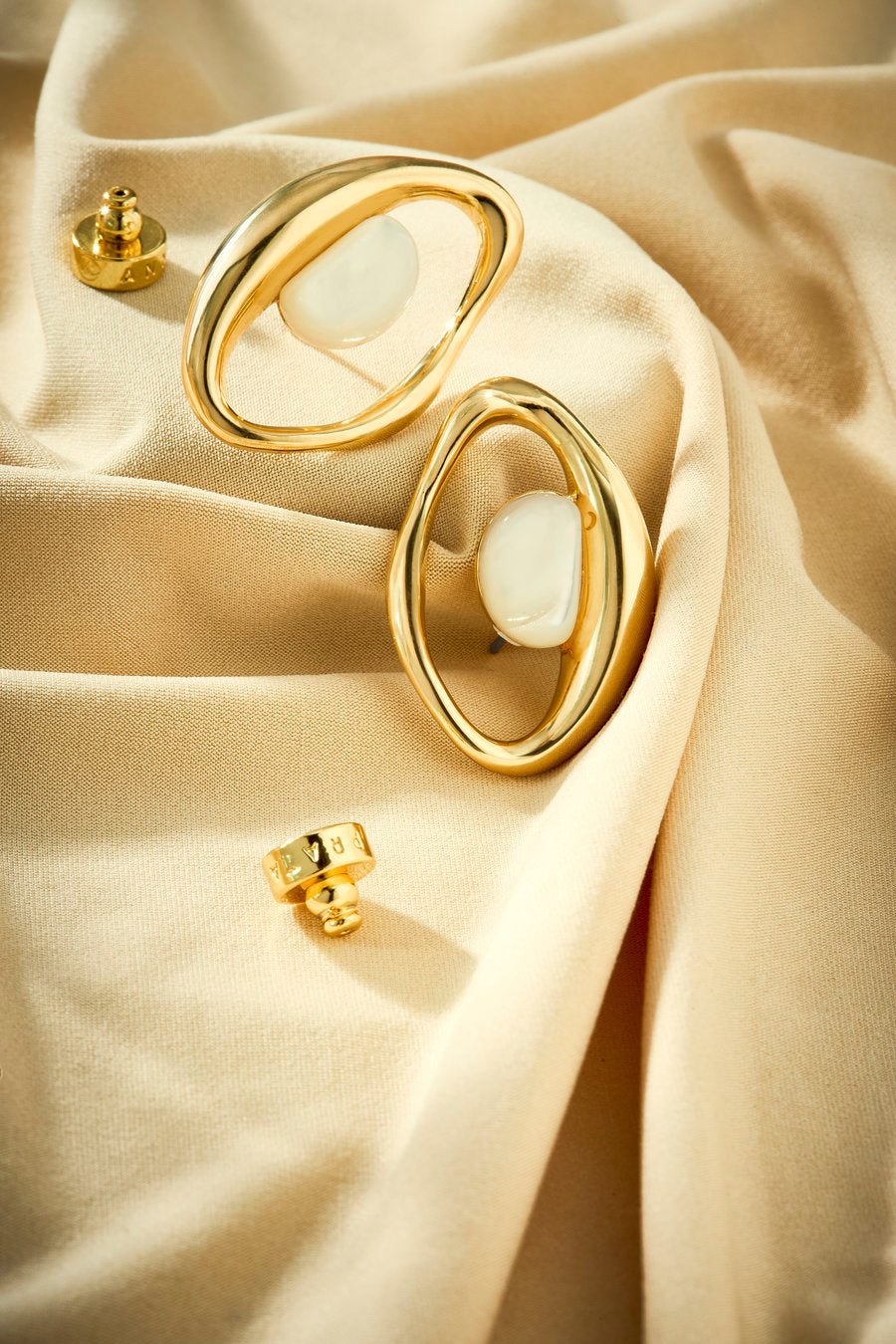 Sculptural gold earring with onyx and flowing curves.
