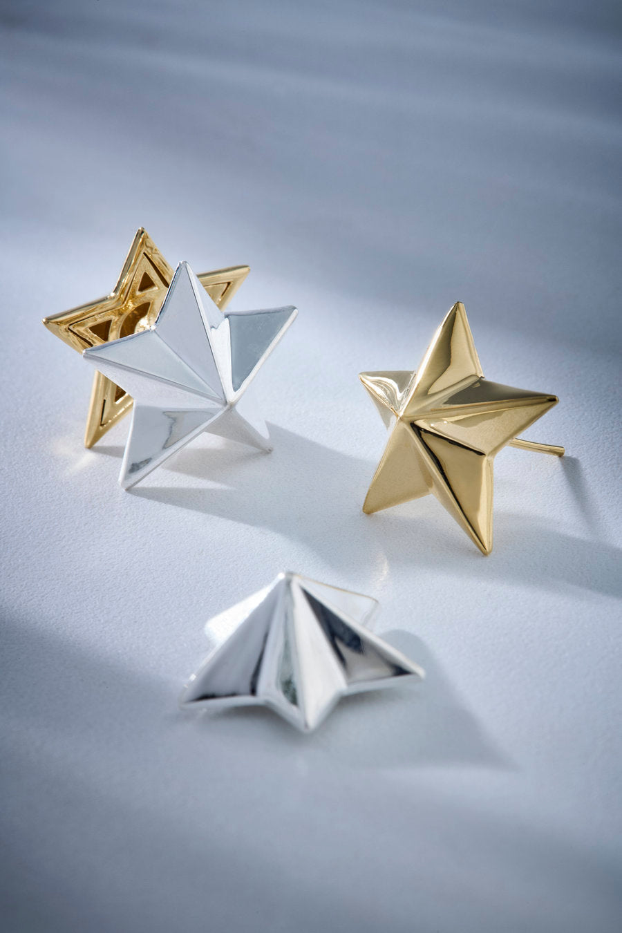 Star-shaped earrings with a polished gold and silver finish, inspired by celestial symbols.
