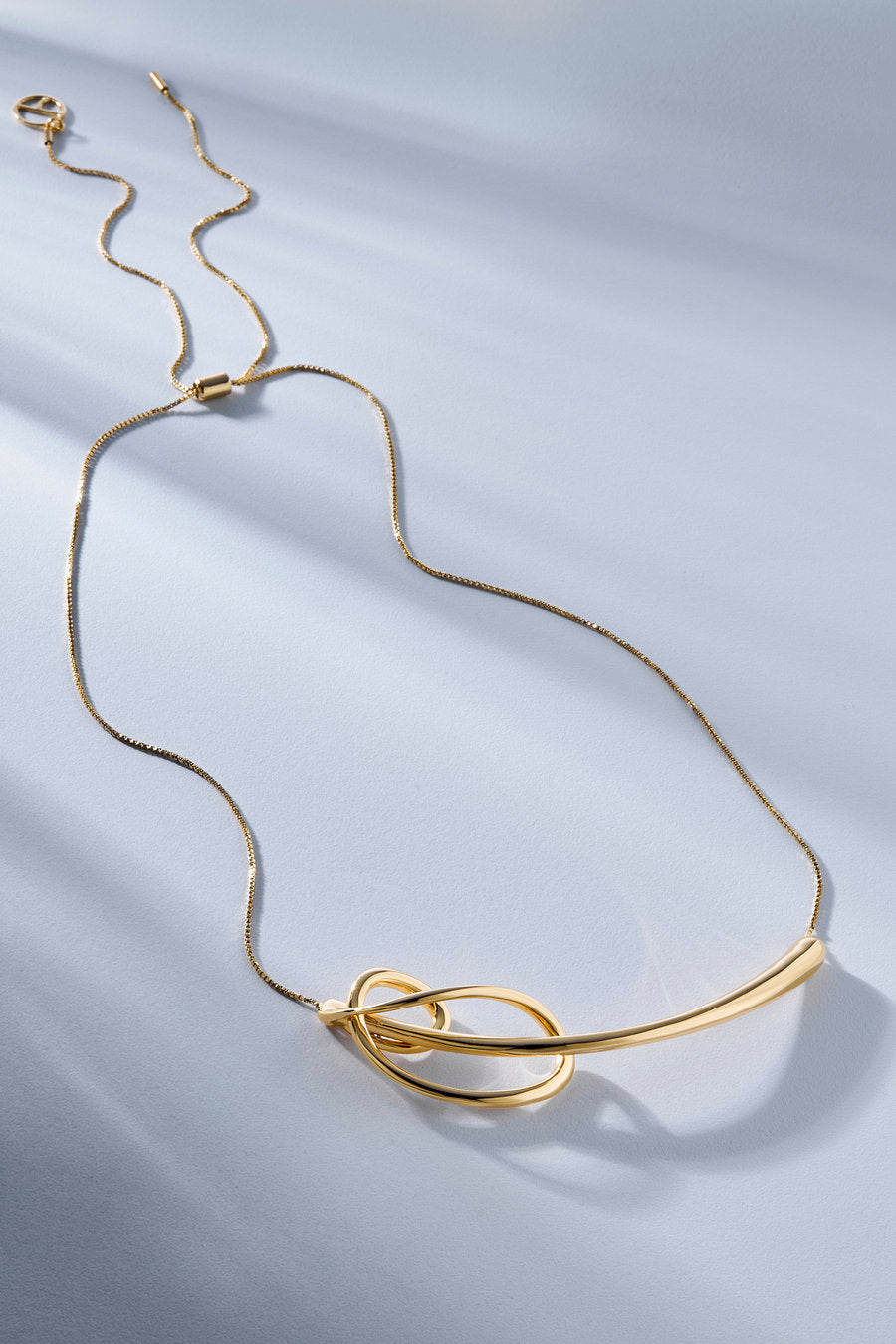 Gold Amparo Necklace – a contemporary piece featuring intertwined curves and a delicate chain.
