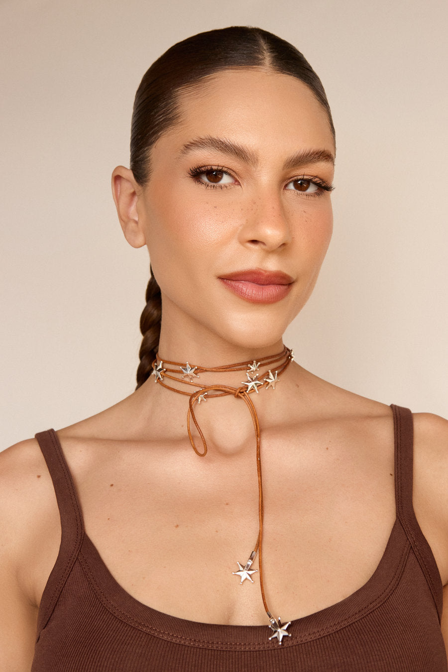 Necklace made of brown cords with several polished silver stars distributed across the front and ends finished with metallic stars.
