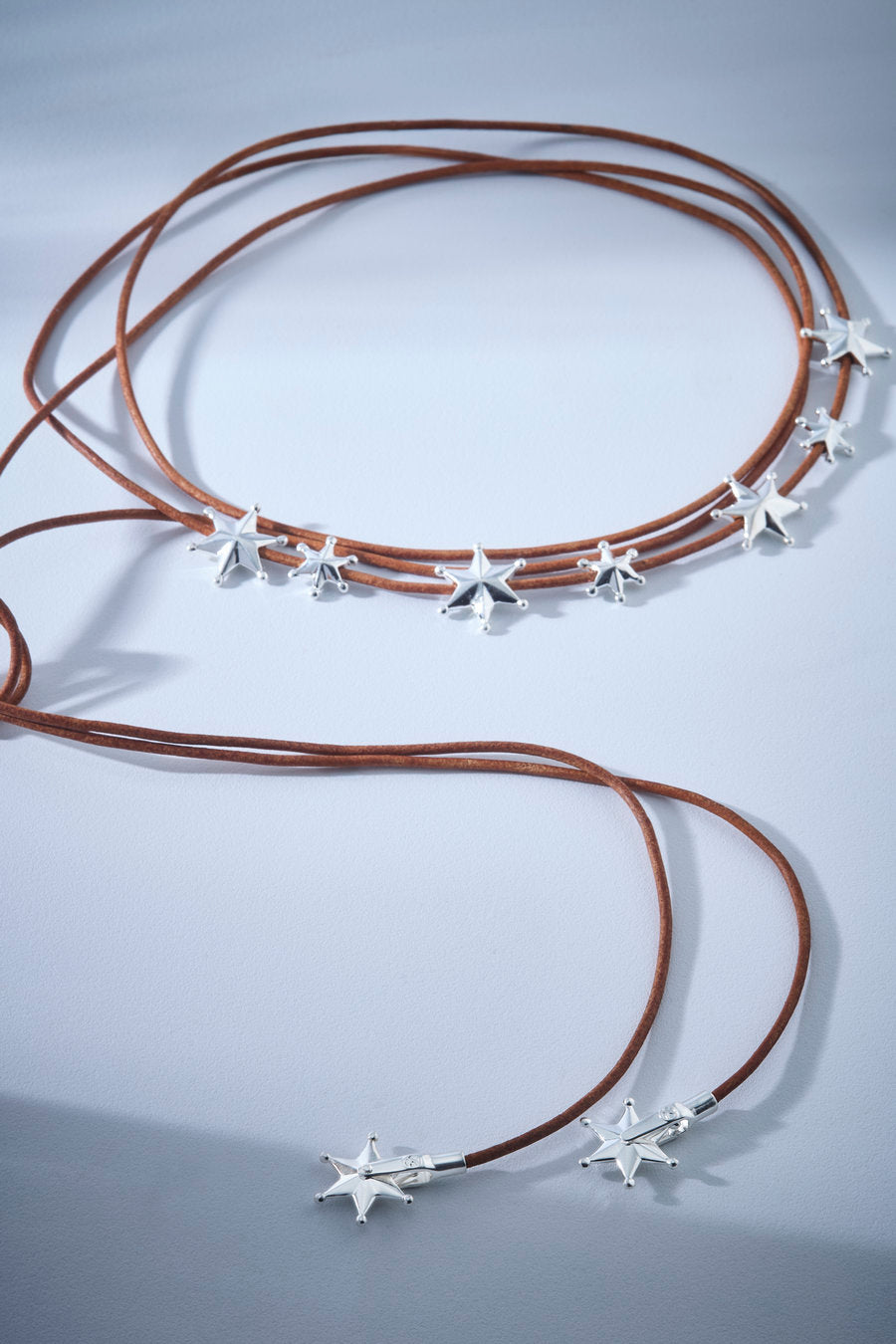 A necklace of brown cords with gold stars that combines celestial themes with a contemporary look. A striking, lightweight, and versatile piece, ideal for modern outfits with personality and presence.
