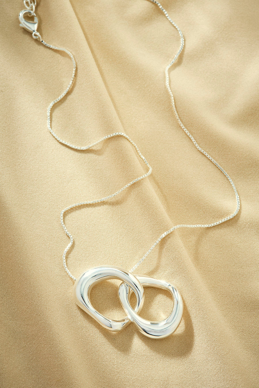 Original silver necklace with intertwined links and a contemporary aesthetic.
