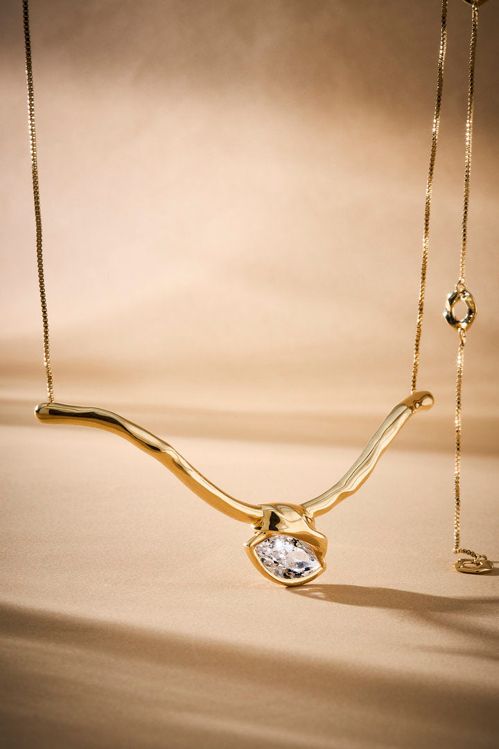 Gabrielle choker in gold-tone metal, featuring fluid lines and a central crystal.