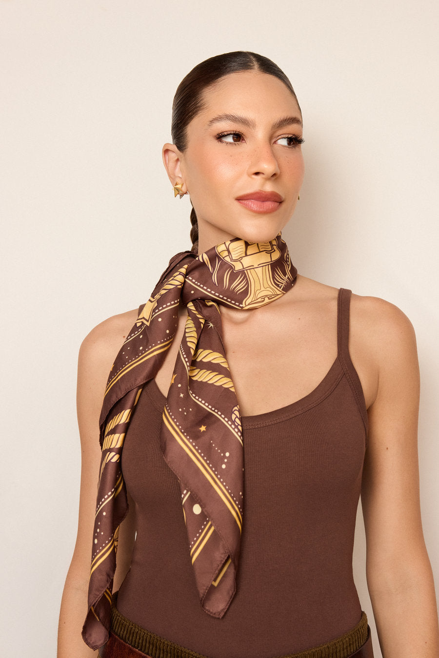Brown scarf with a celestial print in gold, featuring stars, arabesques, and ornamental details. An elegant and versatile accessory, inspired by direction, brilliance, and purpose, to transform outfits with sophistication.