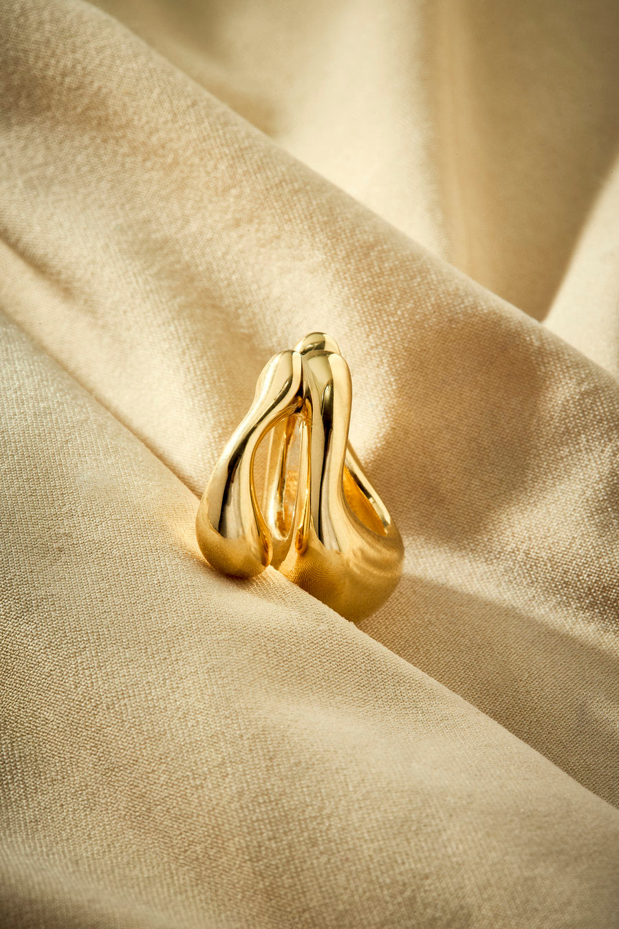 Gold-tone metal memory piercing with a fluid and enveloping design.
