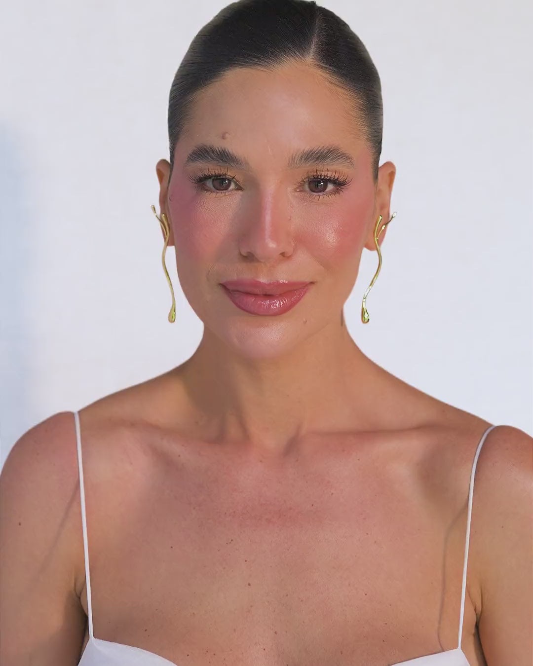 Earring featuring an organic, sculptural design with intertwined lines, a cutout silhouette, and a polished gold finish. The piece conveys connection, movement, and the strength of roots within a contemporary composition.