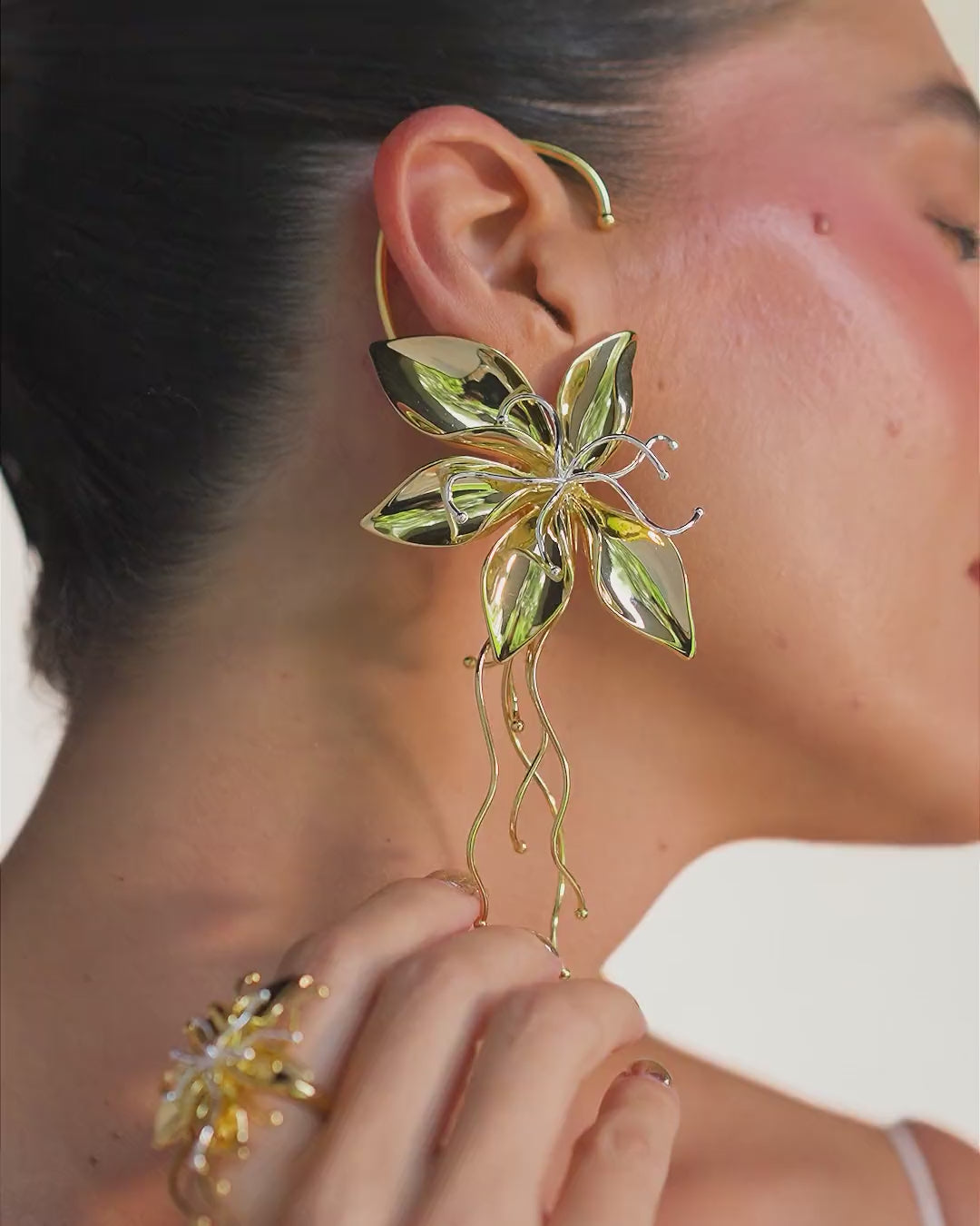  Gold Renascer Earring – sculptural floral design featuring petals, leaves, and elongated, flowing strands.