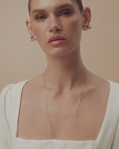 Elsa necklace in gold and white gold, featuring an organic pendant and a faceted crystal that rests against the body like a gesture of light.