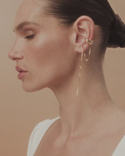 White gold and gold Frida piercing, featuring sculptural curves and fluid chains reminiscent of paint flowing across a canvas.
