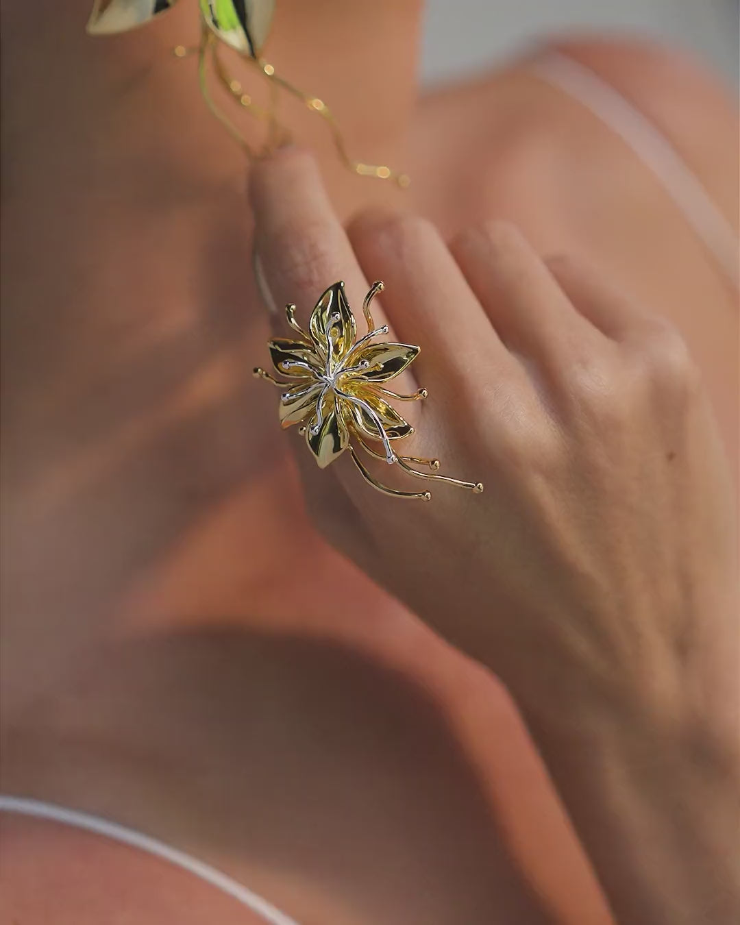 Gold and silver Renascer ring – sculptural floral design with petals, leaves, and an adjustable band.