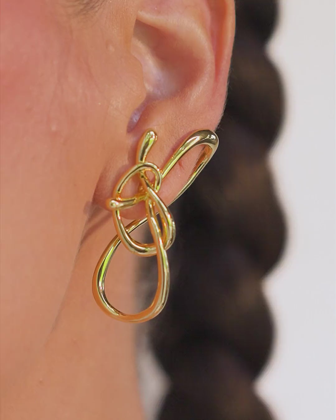 A silver earring with an organic, sculptural design, featuring sinuous, intertwined lines in an openwork composition. The piece conveys connection, movement, and the strength of roots through a contemporary aesthetic.

