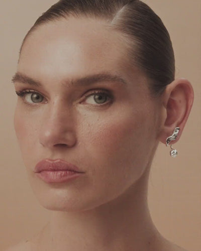 The Frida earring in white fold and gold  features free-flowing curves and sculptural volume that transform the power of painting into movement.